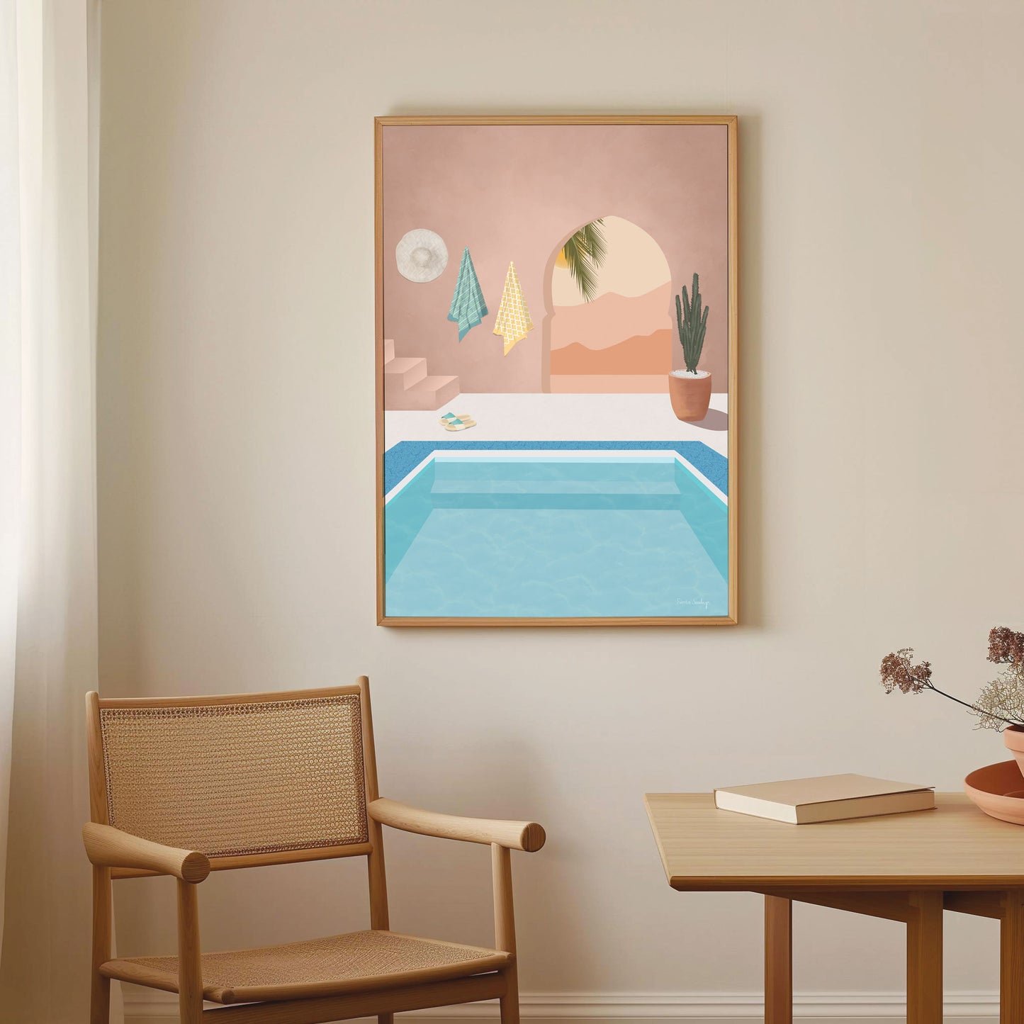 Framed artwork of a pool scene on a wall above a chair and table.