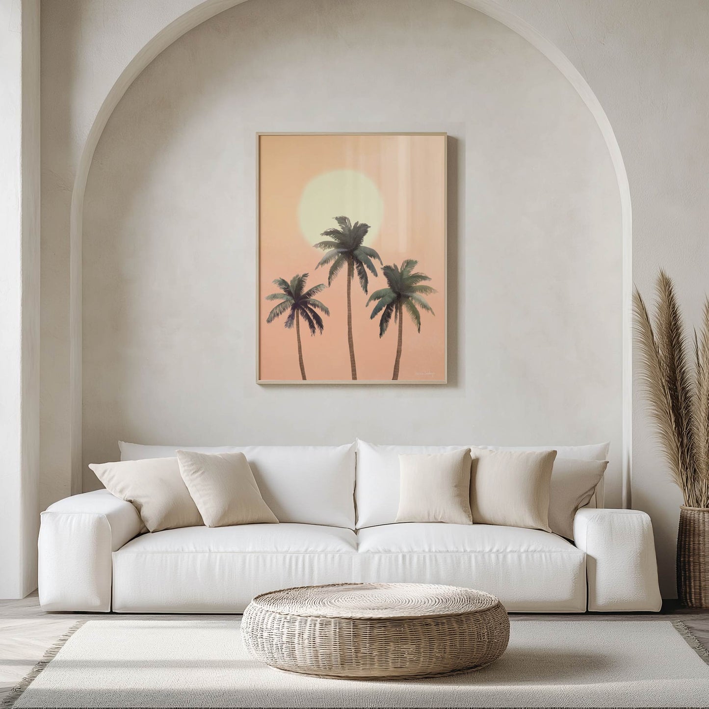 Modern living room with a white sofa, woven coffee table, and wall art of palm trees.