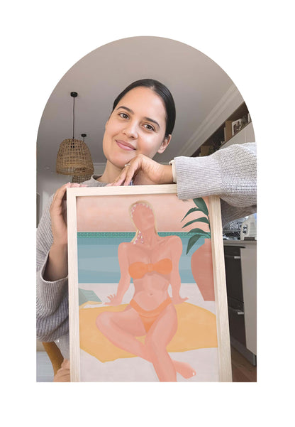 Woman holding a framed artwork of a woman in a bikini by a pool