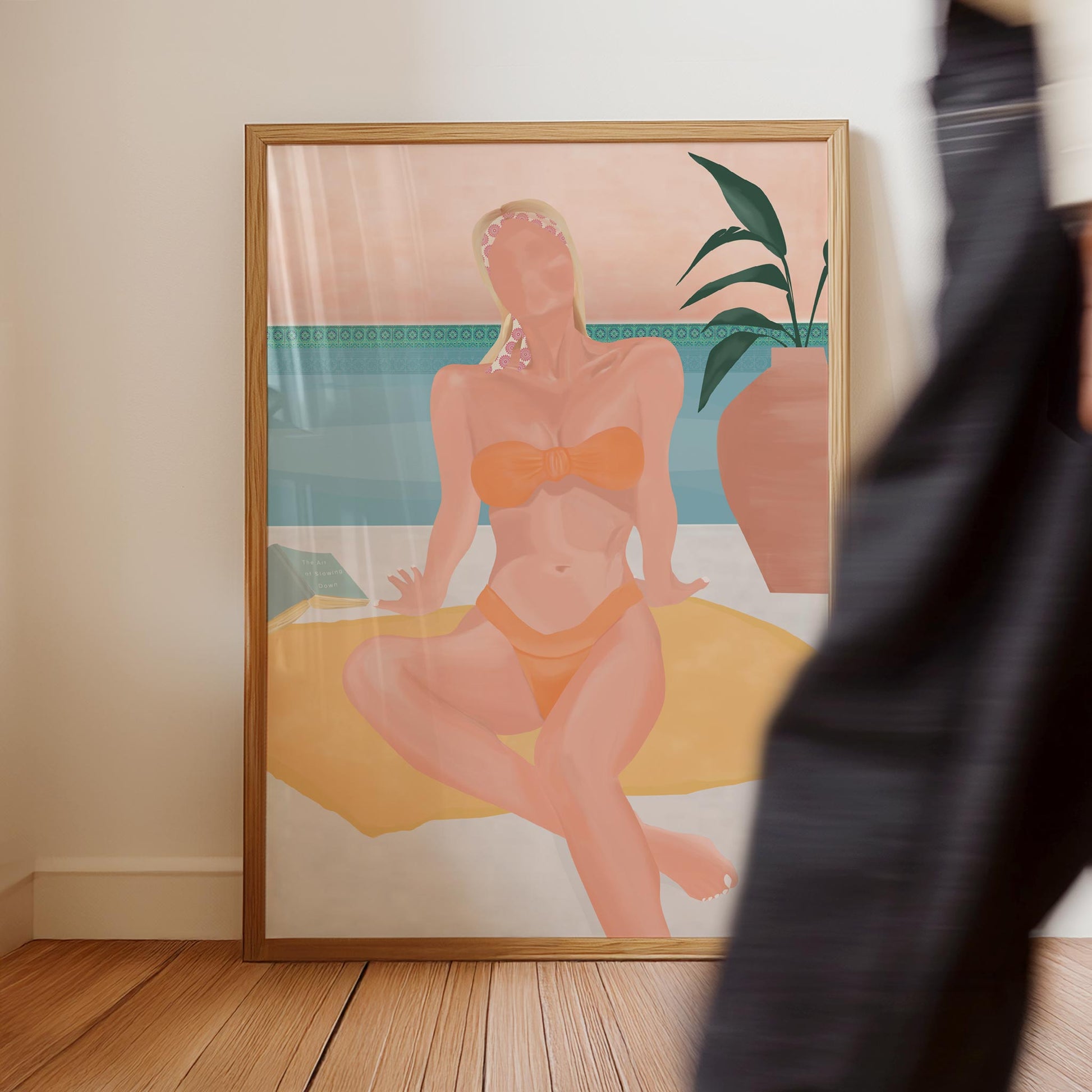 Framed artwork of a woman in a bikini sitting by a pool on a wall.