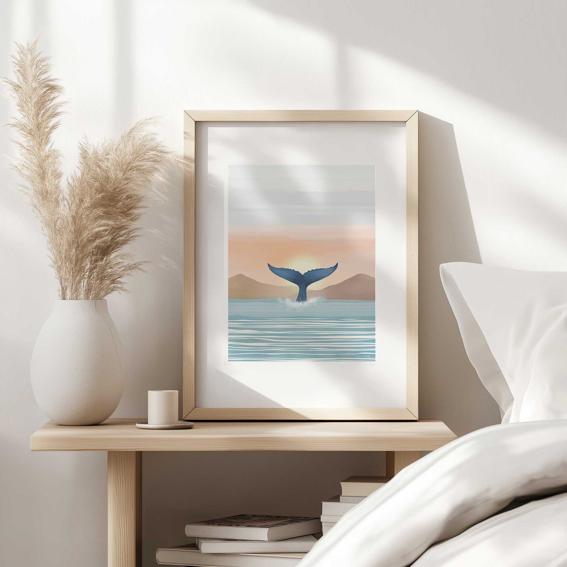 Framed artwork of a whale tail emerging from water on a bedside table.